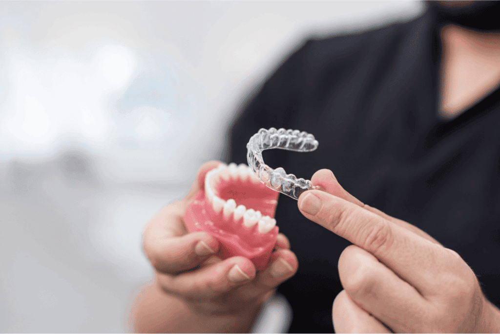 Dentist holding Invisalign or OrthoFX aligners.