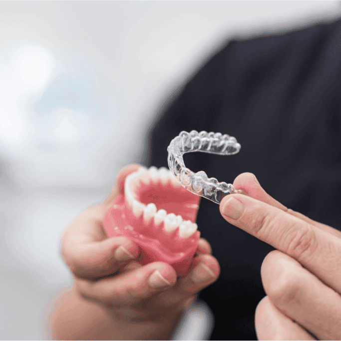 Dentist holding Invisalign or OrthoFX aligners.